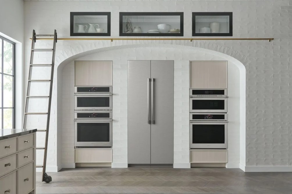 Stainless steel Monogram column refrigerators are built into a farmhouse kitchen with other Monogram appliances