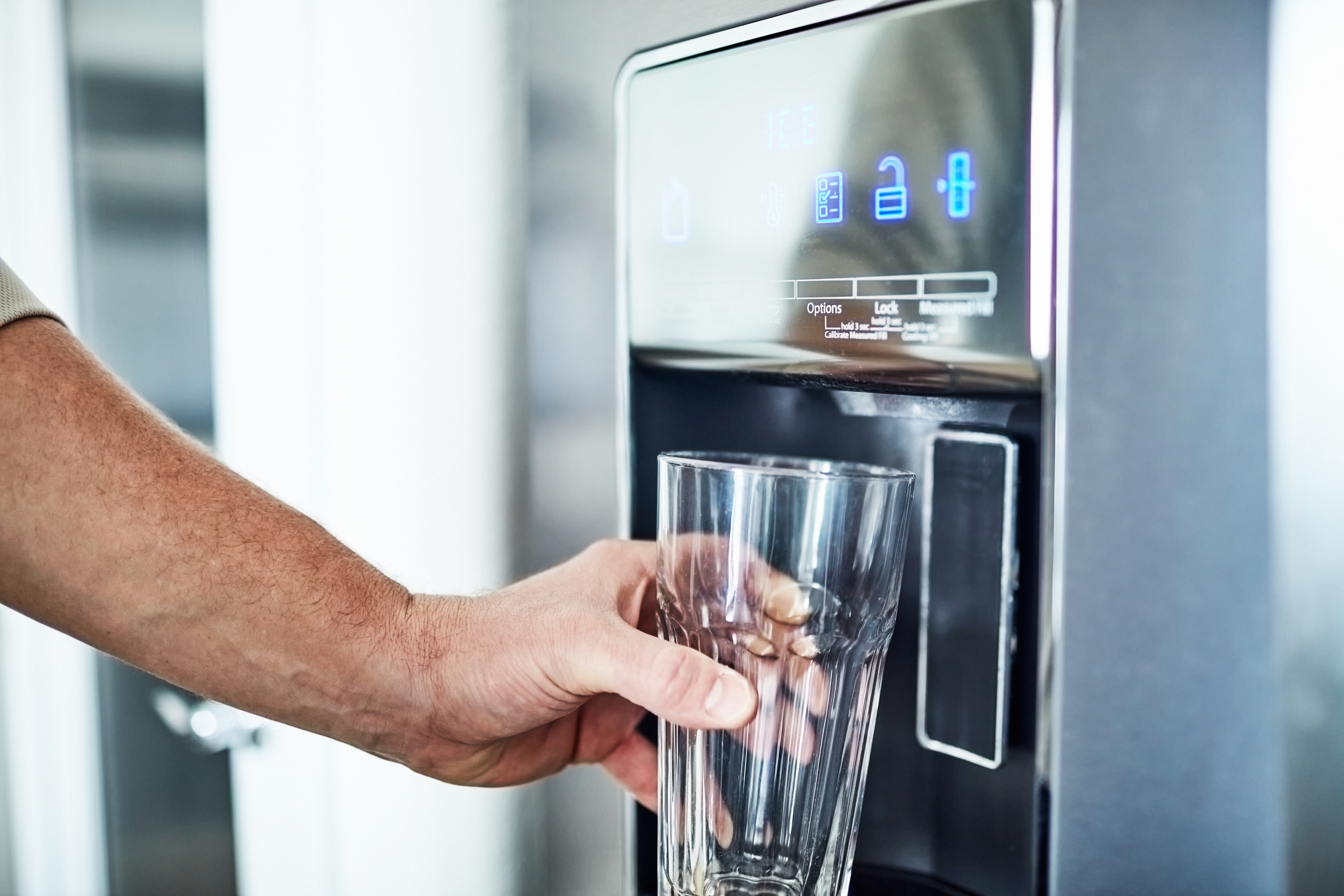 A person using a refrigerator water dispenser 