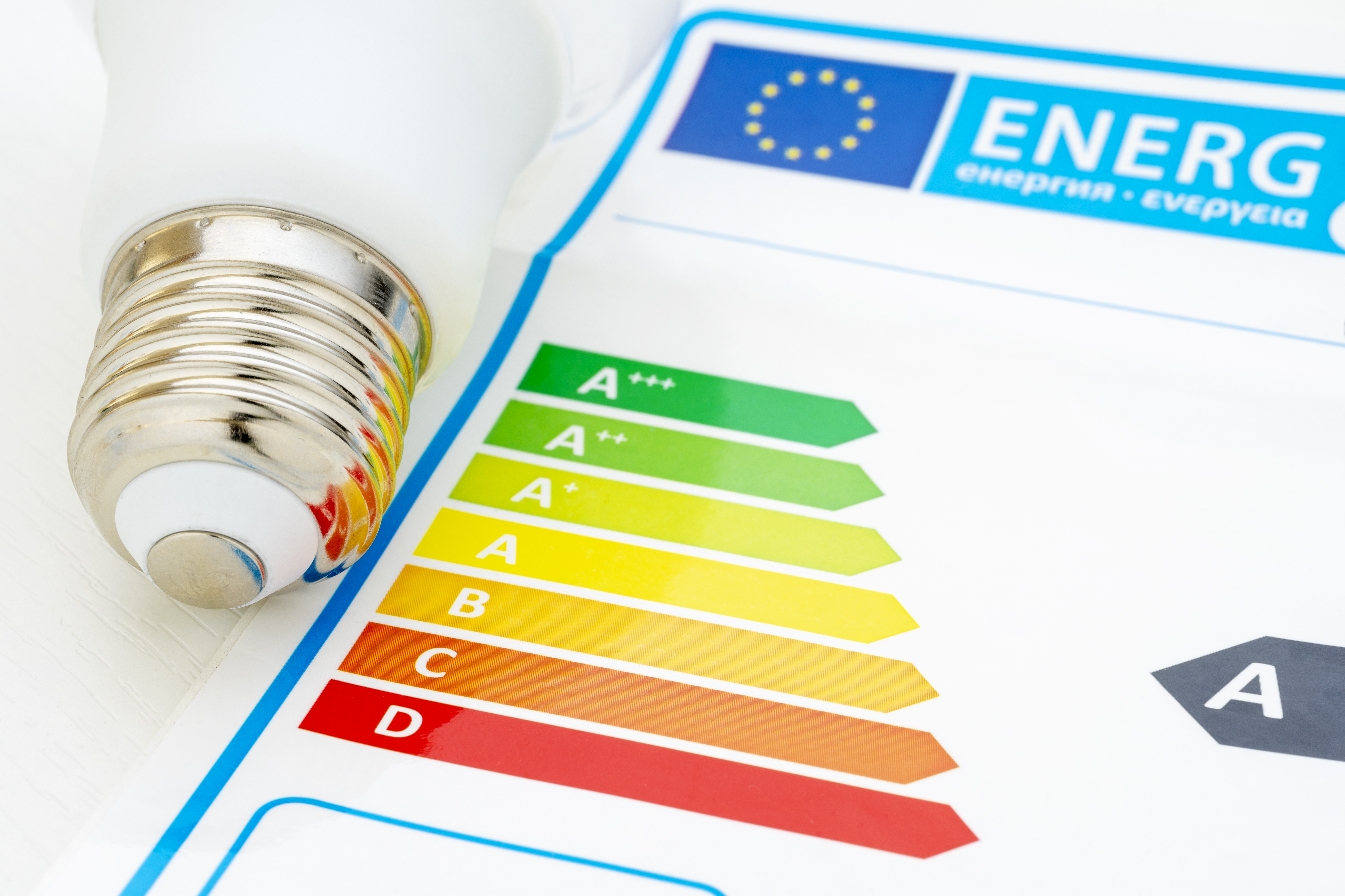 A lightbulb next to an energy label guide with various letter ratings 