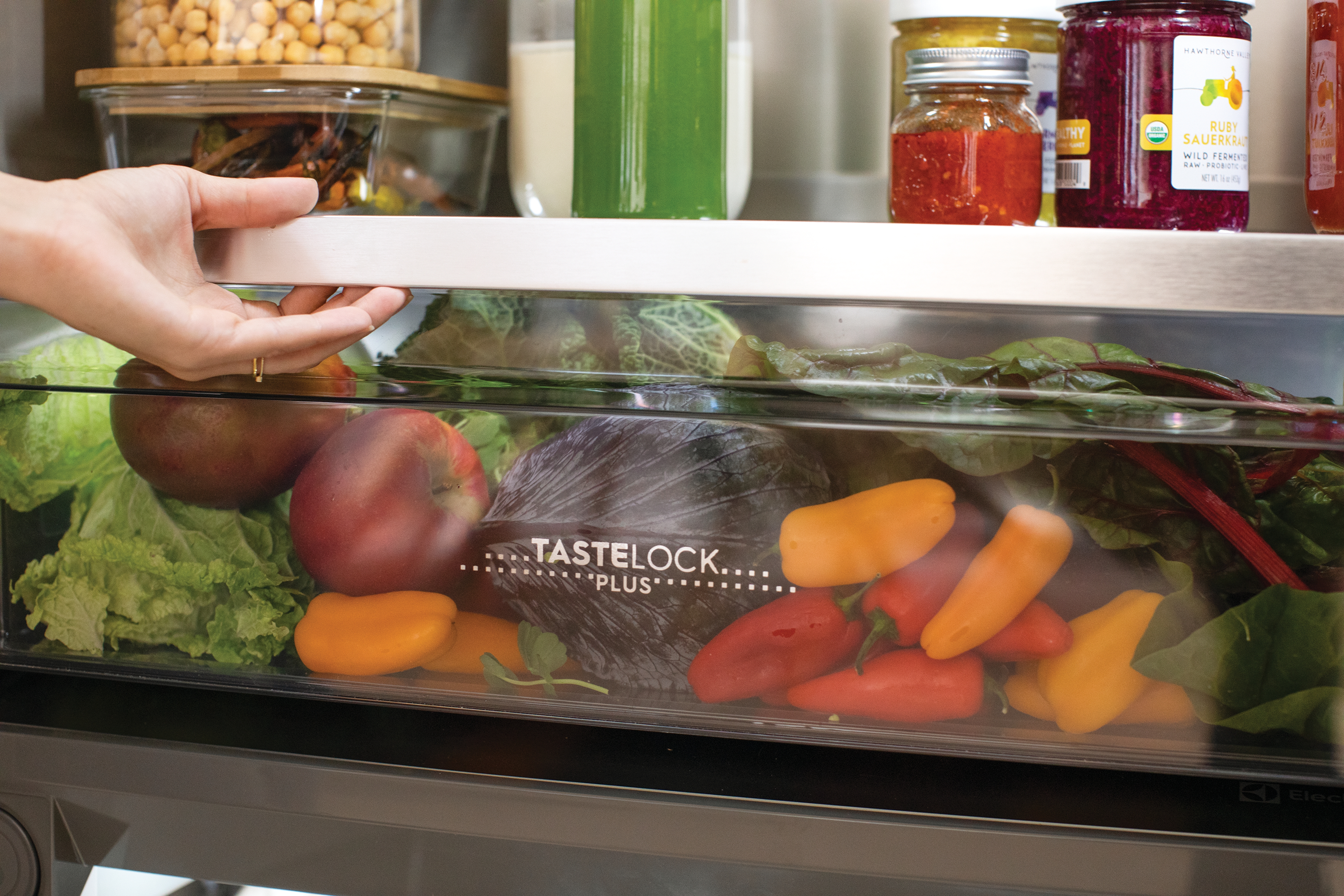 Person reaching for produce inside an Electrolux EI33AR80WS TasteLock crisper drawer 