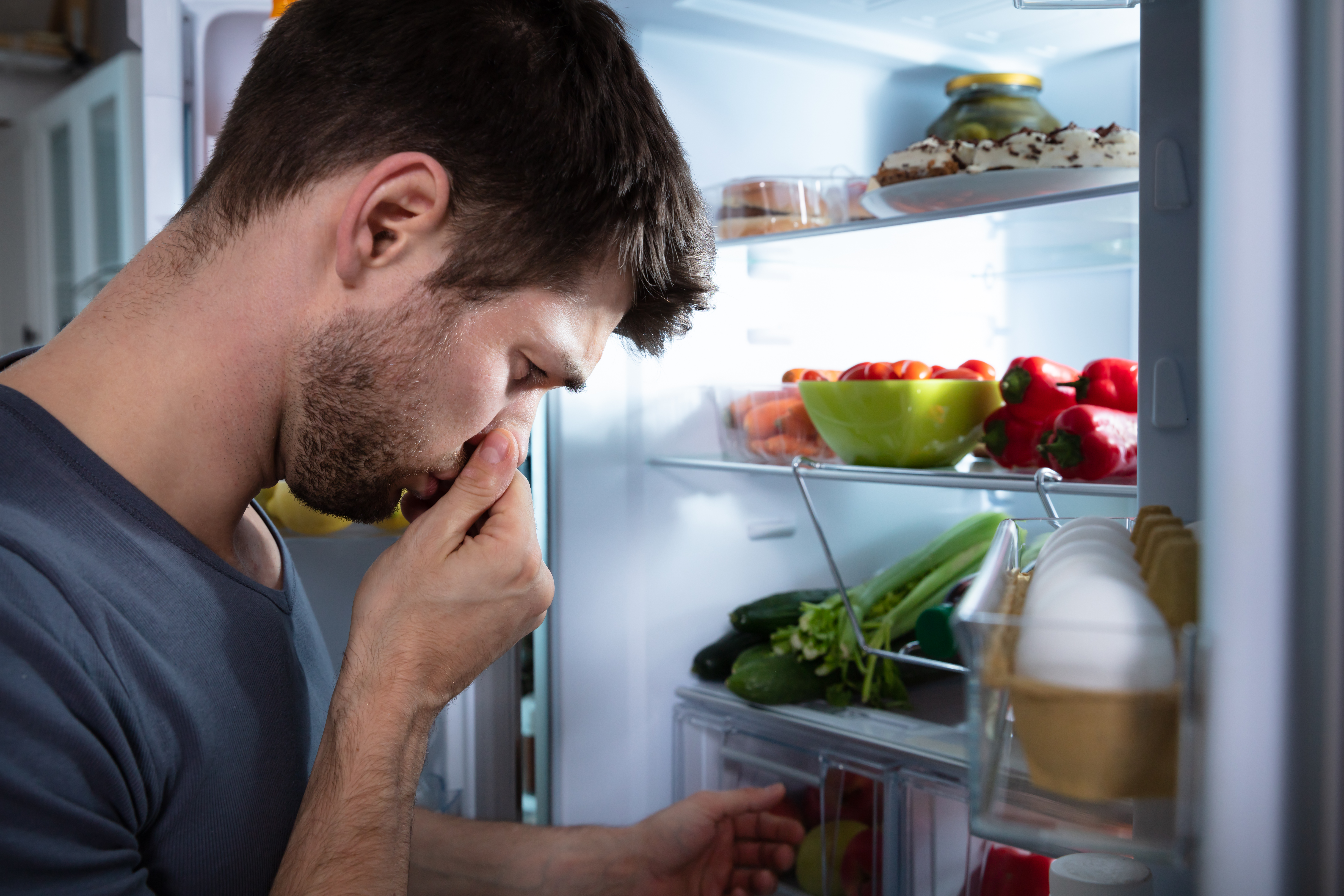 Man holds nose from a stinky fridge 