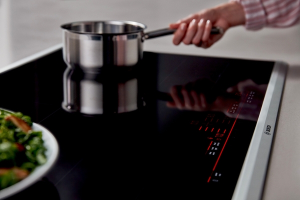 A close up of a woman cooking on a Benchmark induction cooktop 