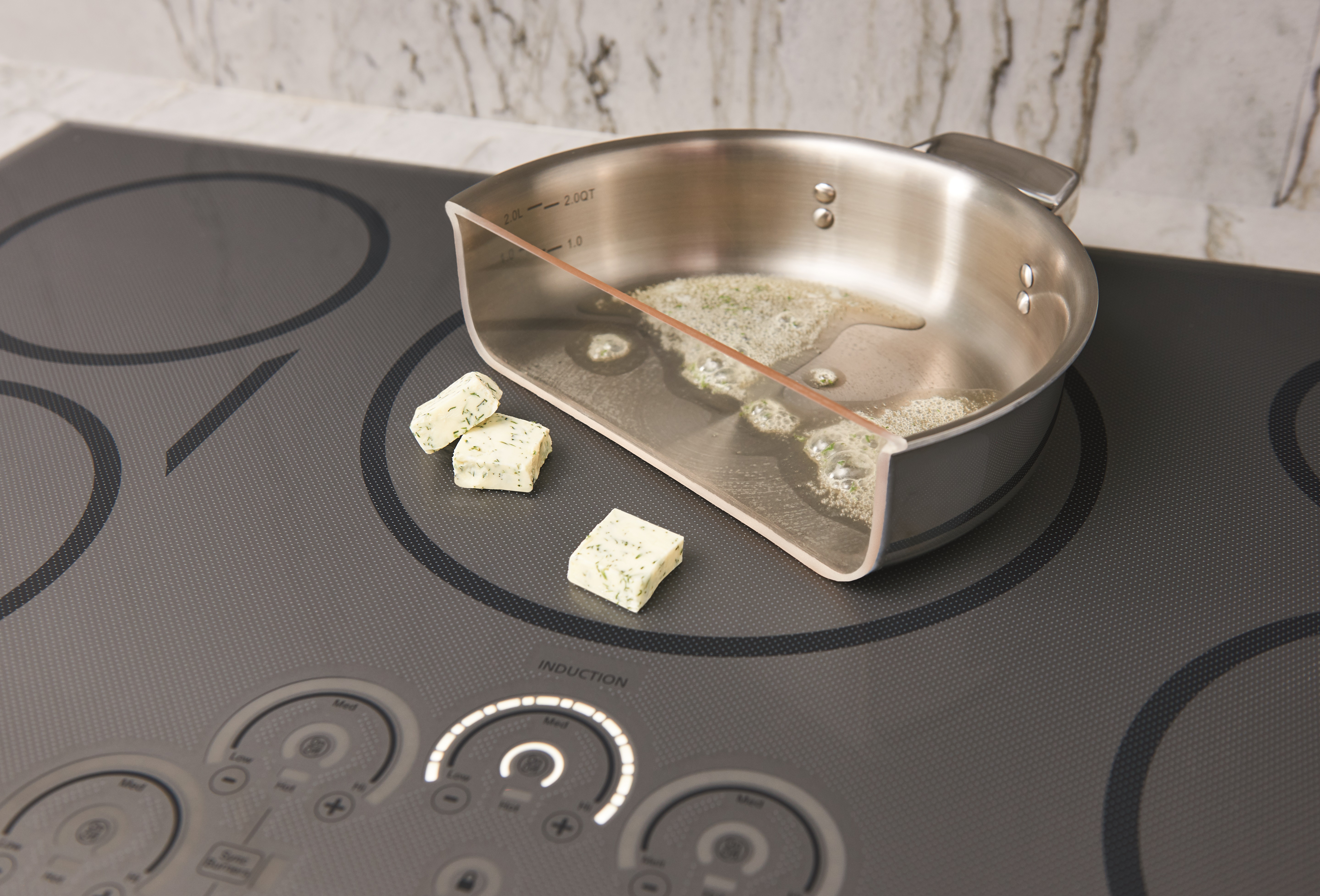 A pan cut in half cooking butter on a GE induction cooktop 