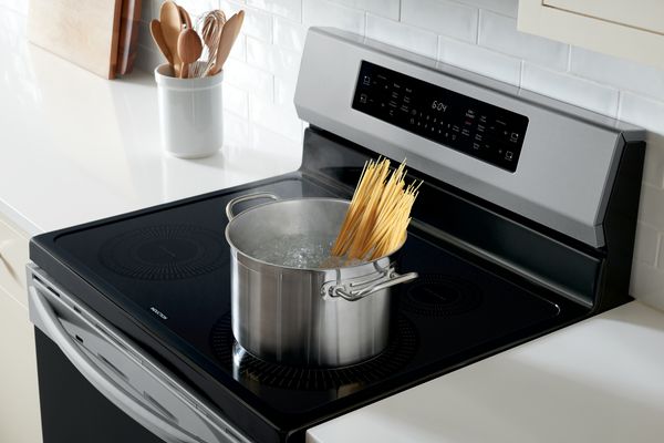 A pot boils water for spaghetti atop a freestanding induction range