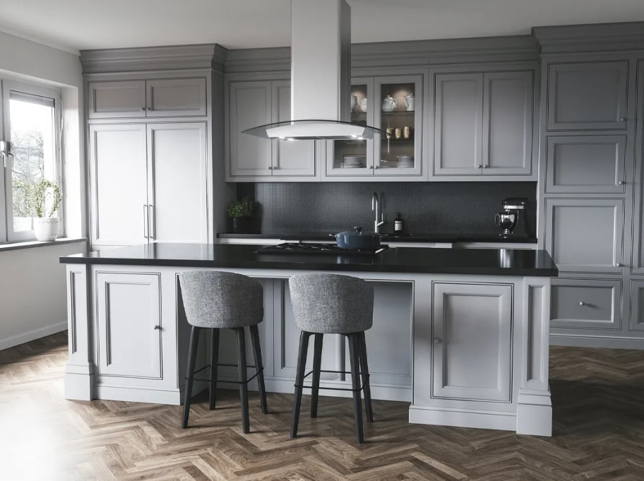 A glass island range hood is featured above an island in an elegant kitchen