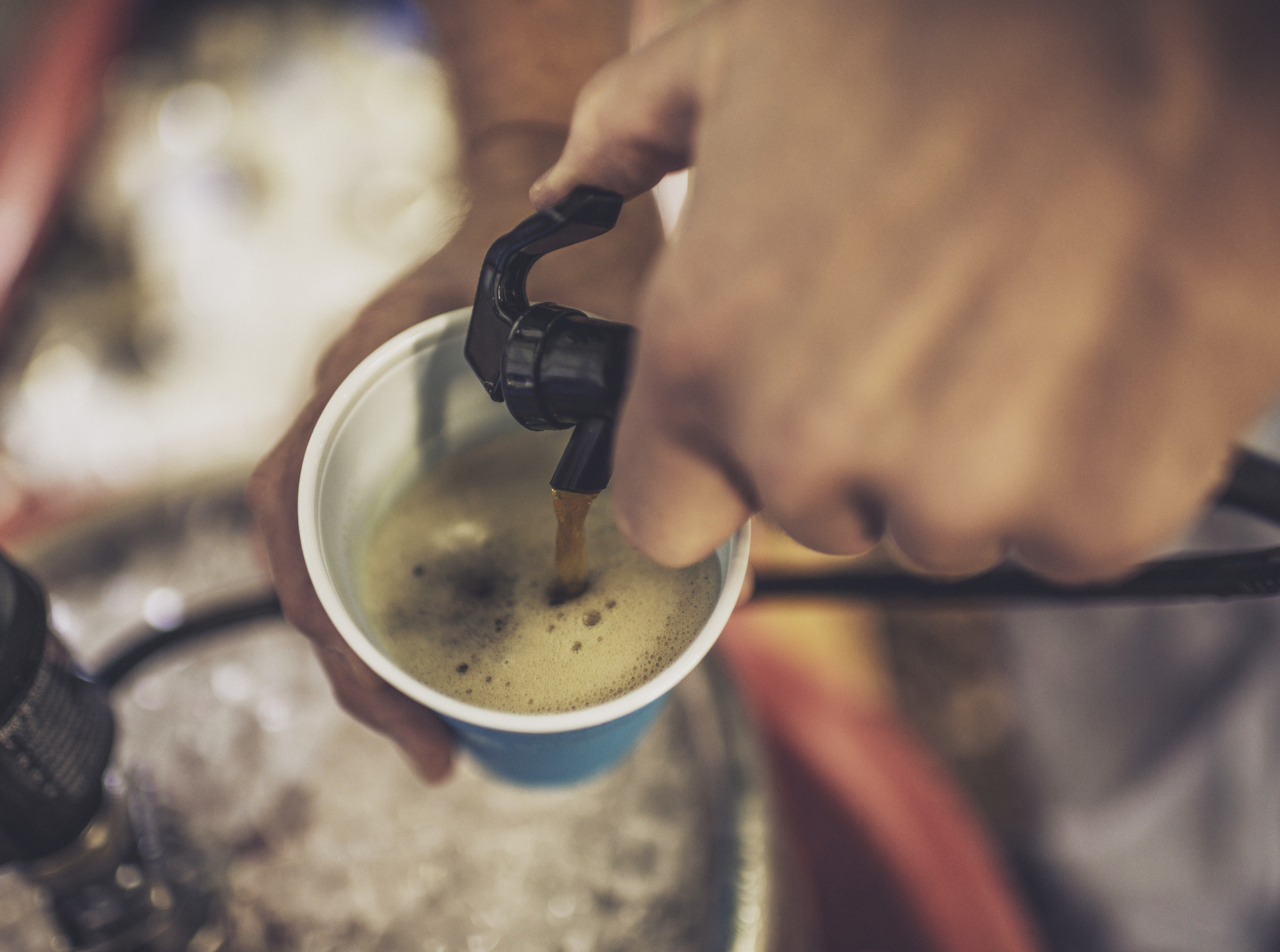 Person pouring beer from a kegerator into a plastic cup 