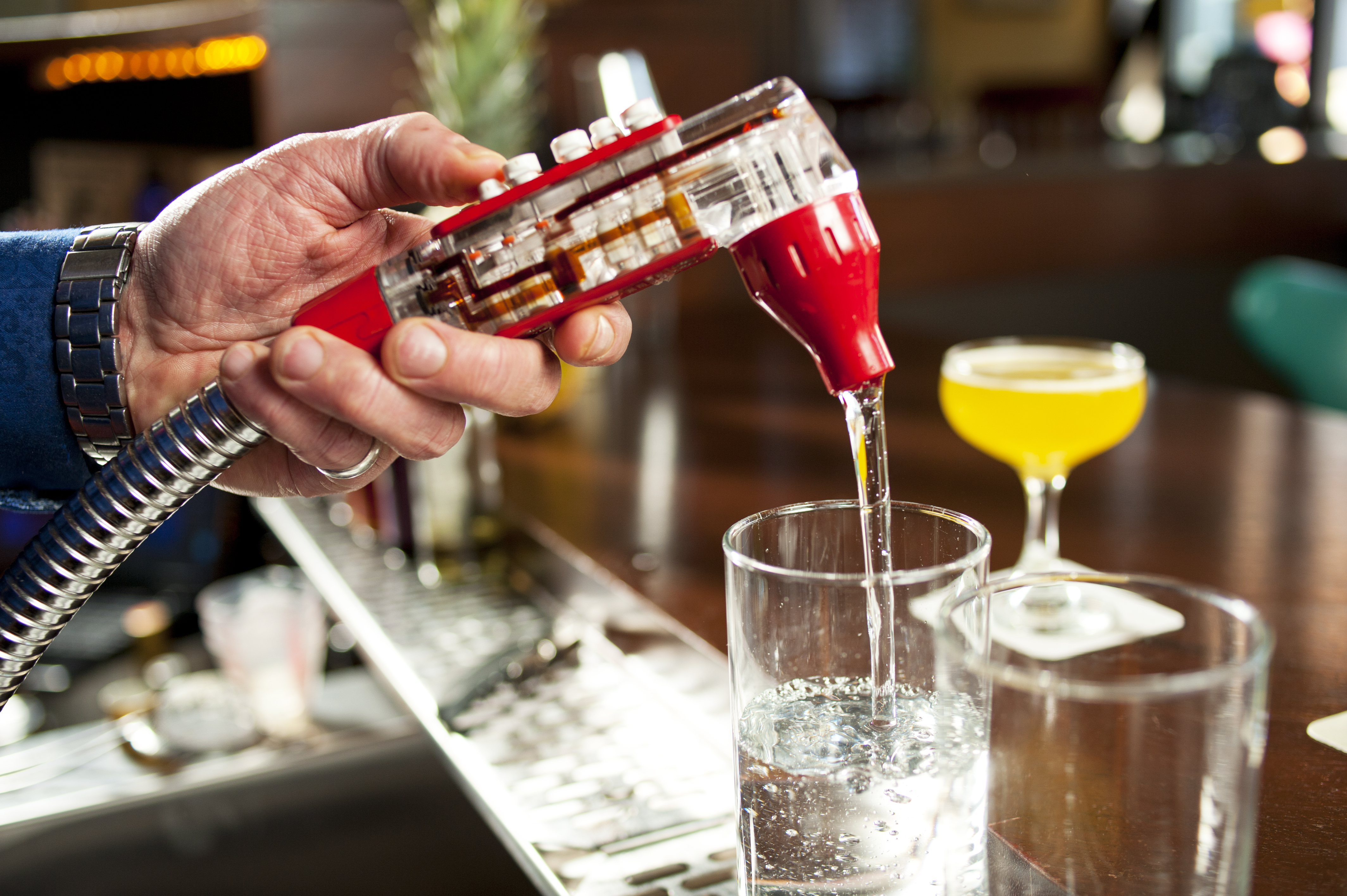 Person pouring water from a bar nozzle into a cup 