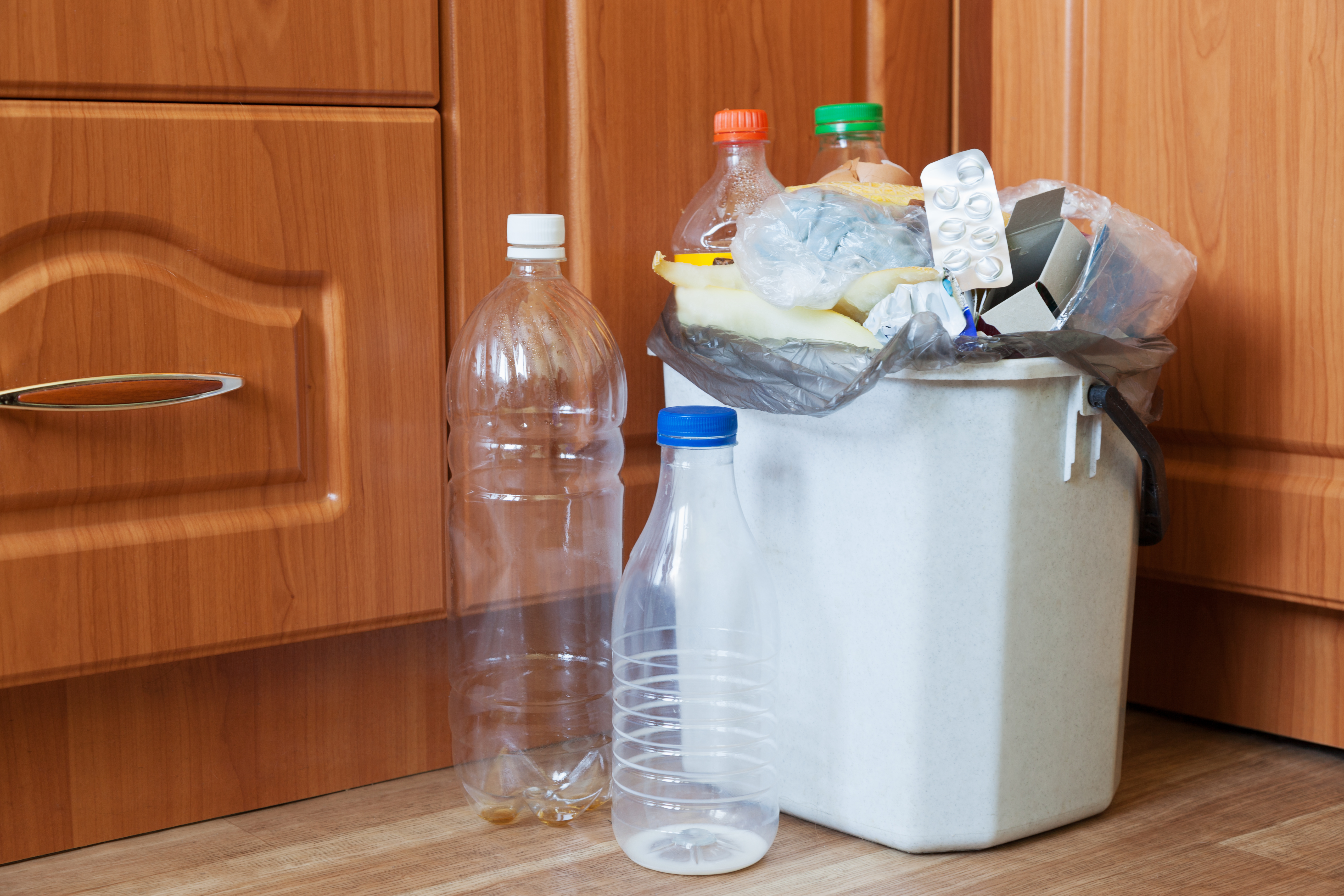 Trash and plastic bottles overflowing from a garage can