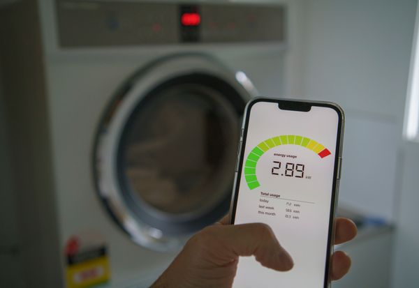 A person holding a smart phone with an energy guide gauge for a dryer 