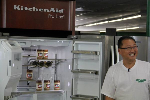 Sam Pak demonstrating a KitchenAid refrigerator in store 