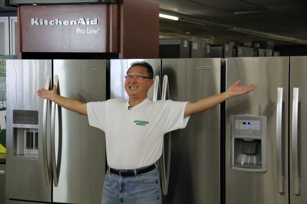 Sam Pak smiling in front of a variety of refrigerators at Appliance Direct 