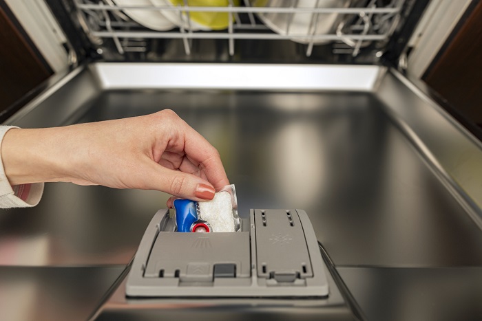 Woman puts the dishwasher pod in the dishwasher before washing.