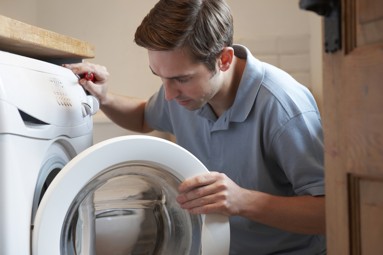 man uses screwdriver to fix his front-load washing machine