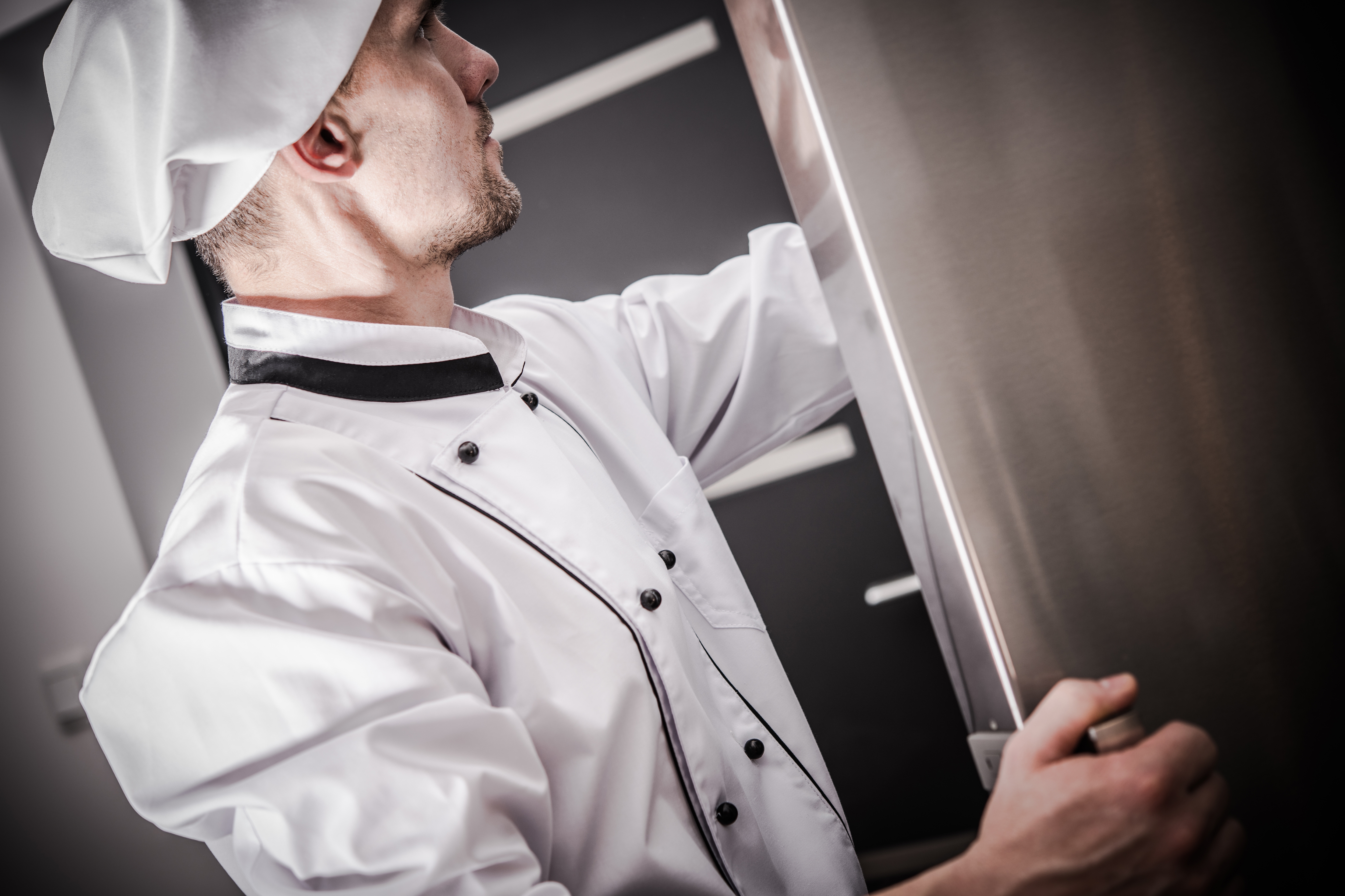 A chef reaching into a commercial refrigerator 