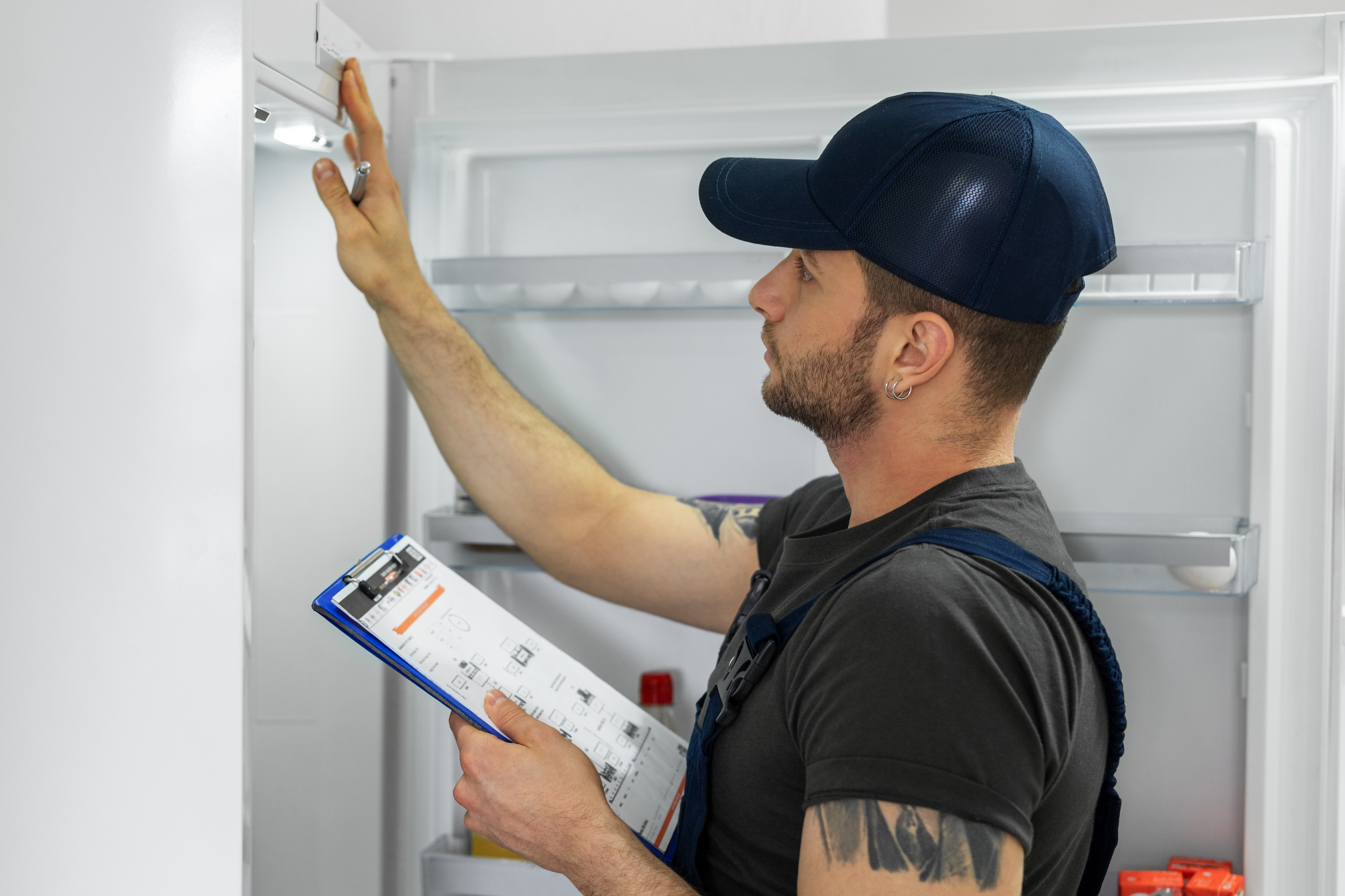 A young appliance repairman inspecting a refrigerator 