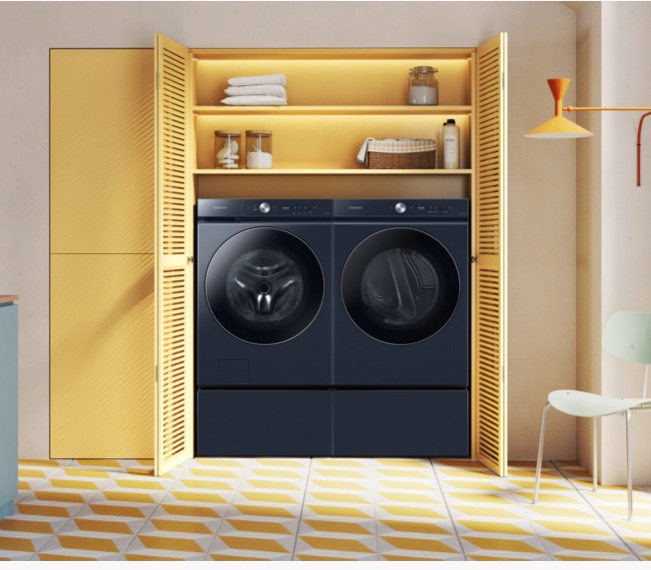 A yellow closet with a black Samsung washer and dryer inside