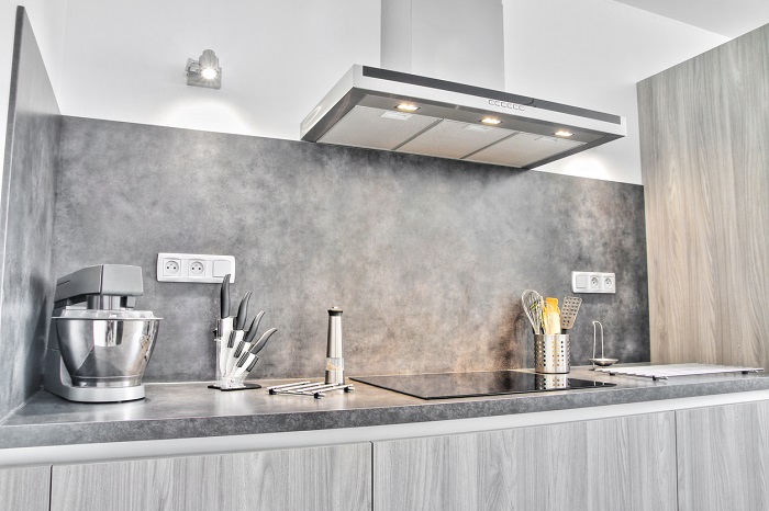 Luxury kitchen with some kitchen utensils, shot in front of the cooking area with range hood.