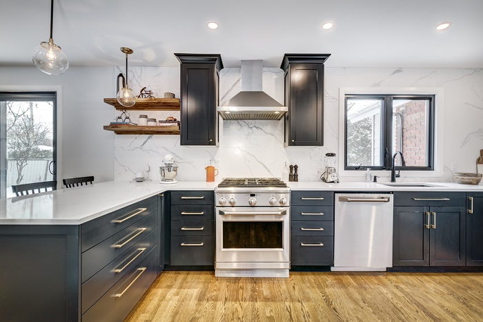 Modern kitchen with hardwood flooring, blue cabinets, and a gas range with overhead mounted range hood.