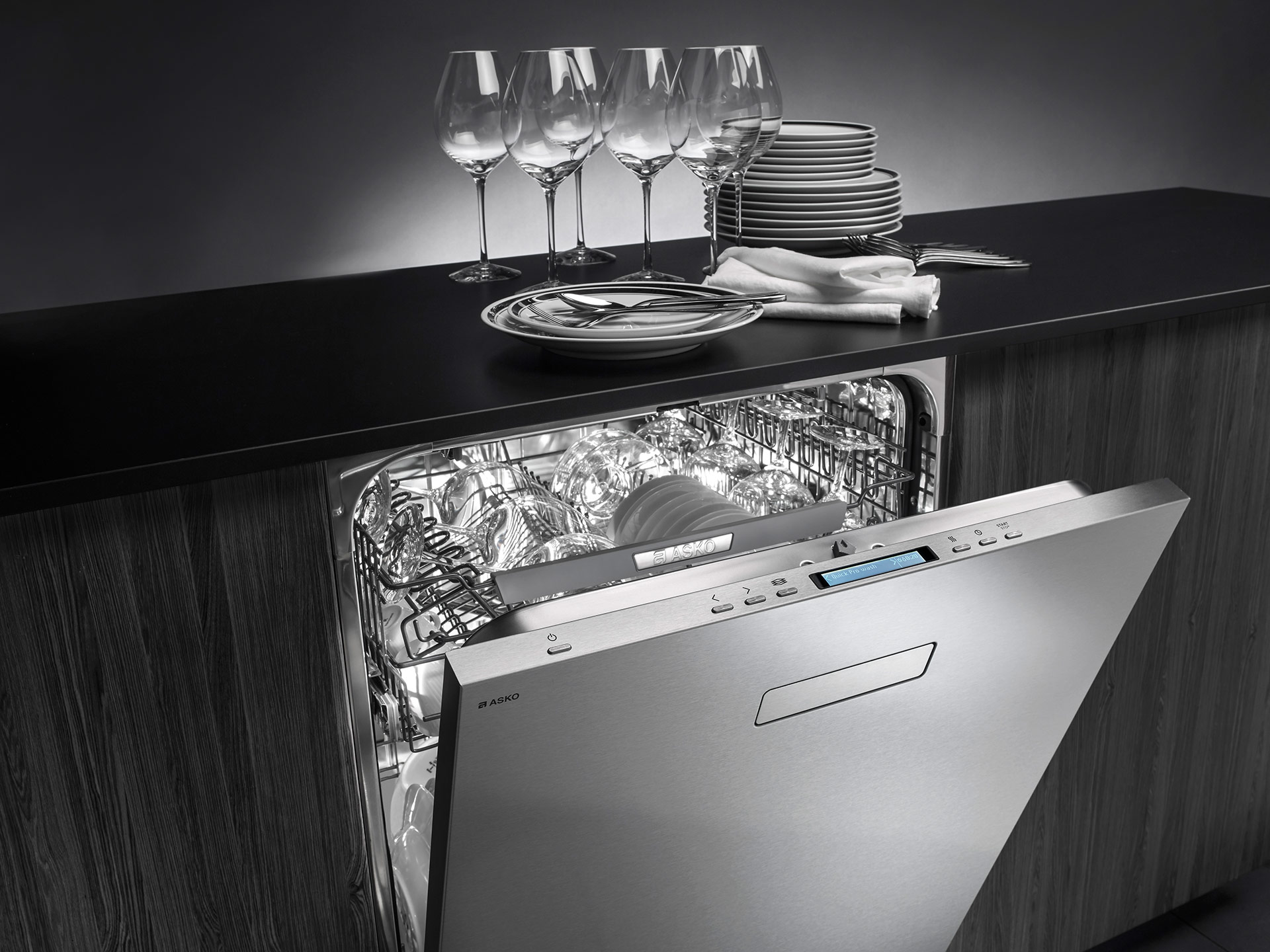 An Asko stainless steel dishwasher shown open and full of dishes 