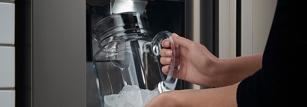 A cup collects ice from an ice dispenser