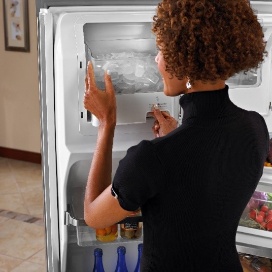 a woman checks the ice dispenser in her refrigerator