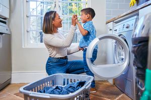 Moyo Studio A mother and child smiling while taking laundry out of a front load washer