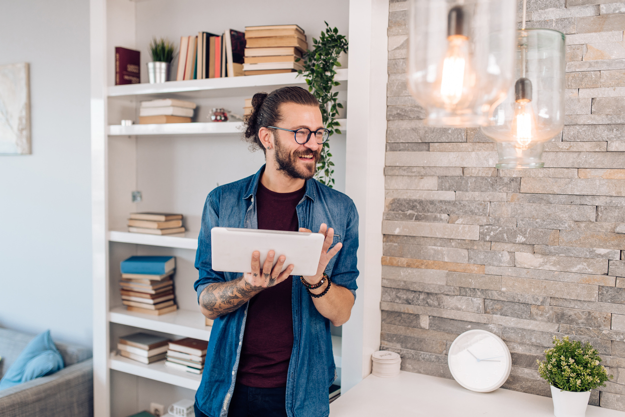 Young man setting up the intelligent home system on a digital tablet.