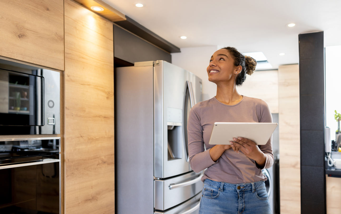 Happy woman controlling the lights of her smart house using an automated system from a tablet computer. 