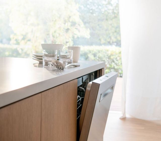 side view of a panel ready built in dishwasher in an island slightly opened