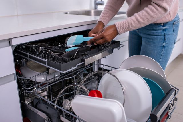 Front view of a woman loading the third rack in her dishwasher