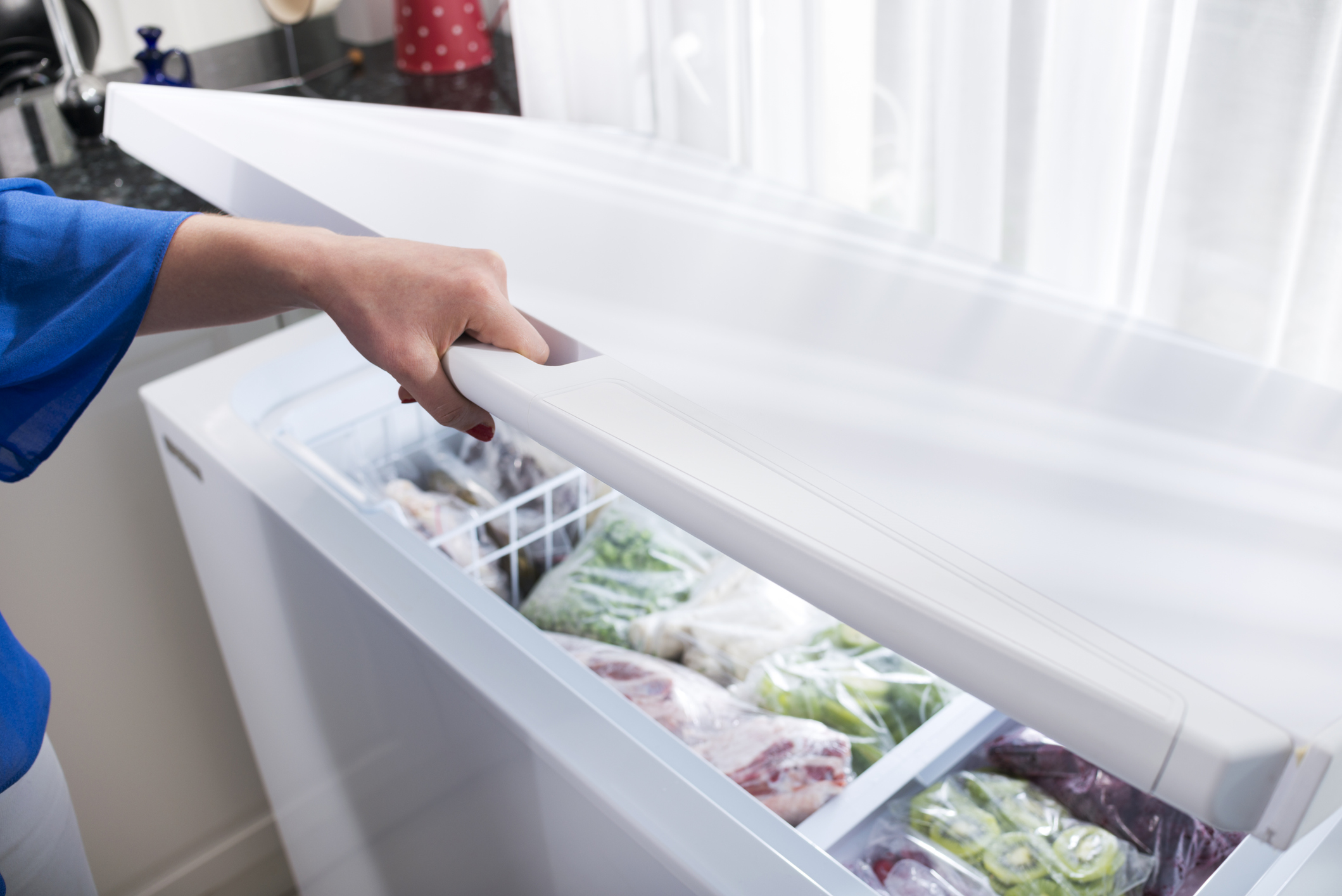 woman opening the door on her chest freezer 