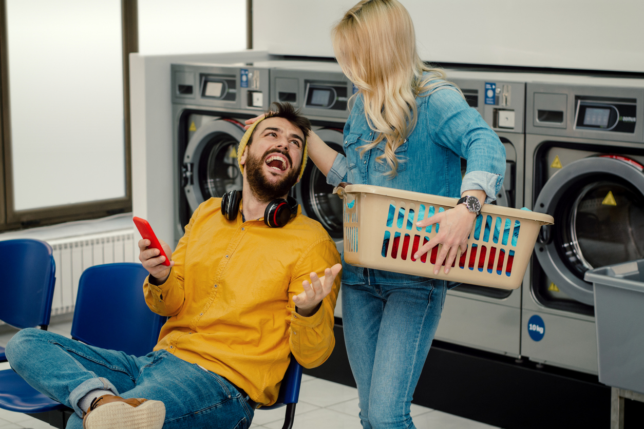 young couple doing laundry in self-service public laundry facility