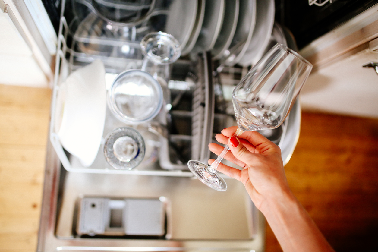 closeup of woman’s hand taking a clean wine glass out of the dishwasher