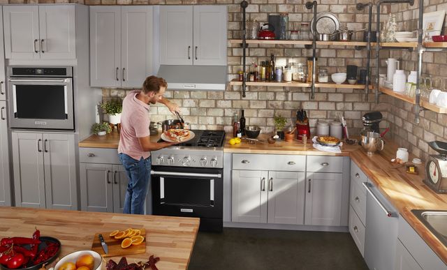 front view of a man cooking in a modern kitchen with a dual fuel range