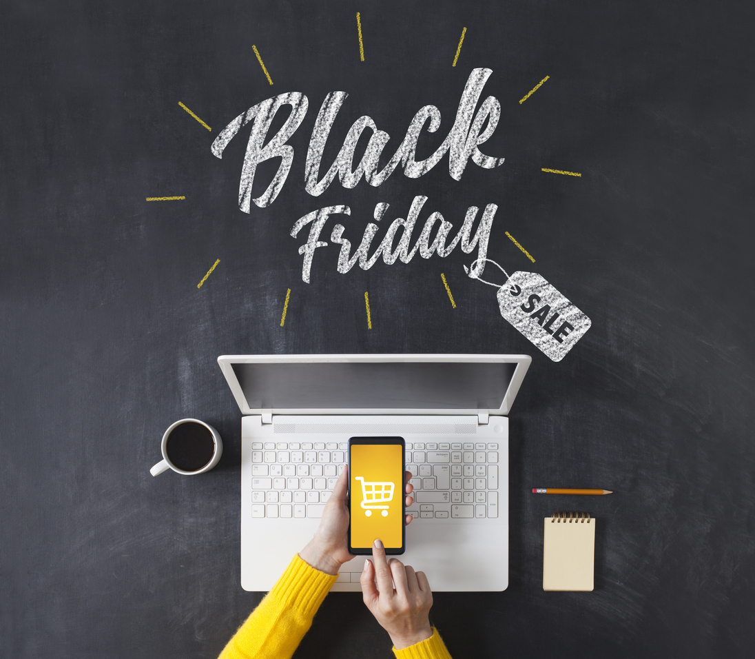 overhead shot of a person's hand shopping on a smartphone with an open laptop and the banner words Black Friday Sale