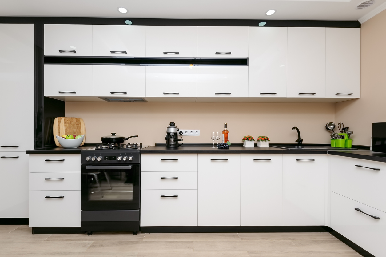 modern spacious kitchen with black range and white cabinetry