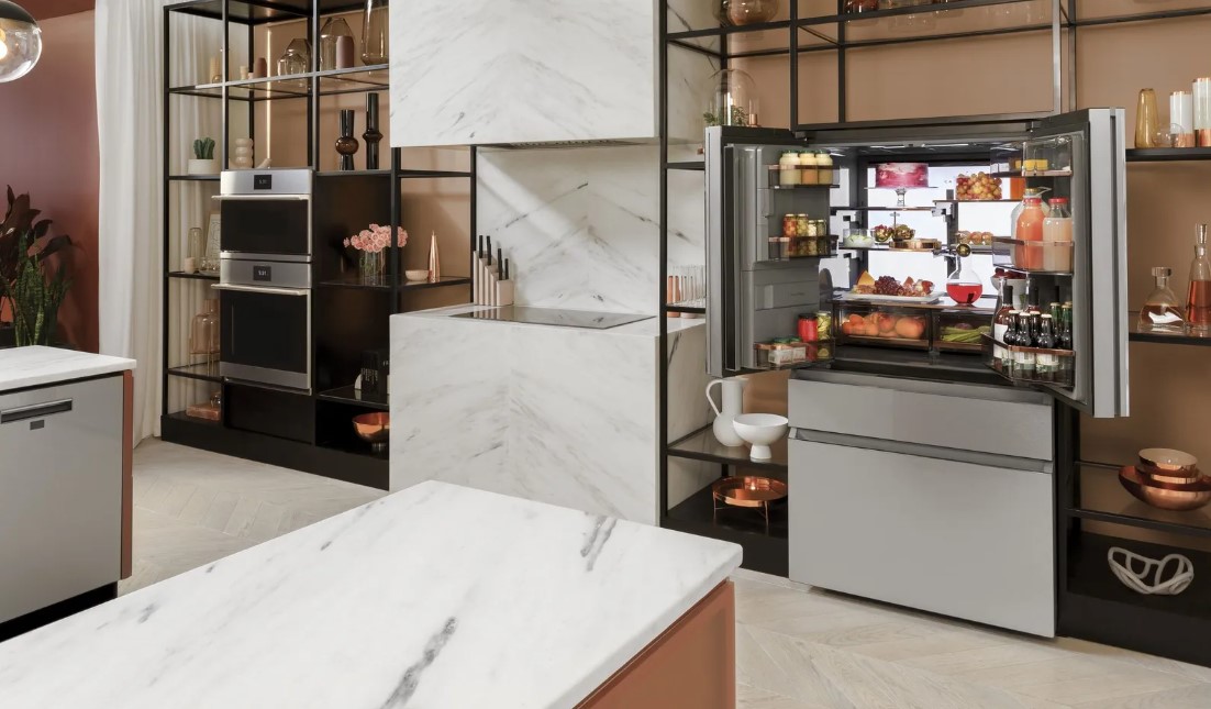 A 4 door Cafe refrigerator with open door is featured in a luxury kitchen with copper accents