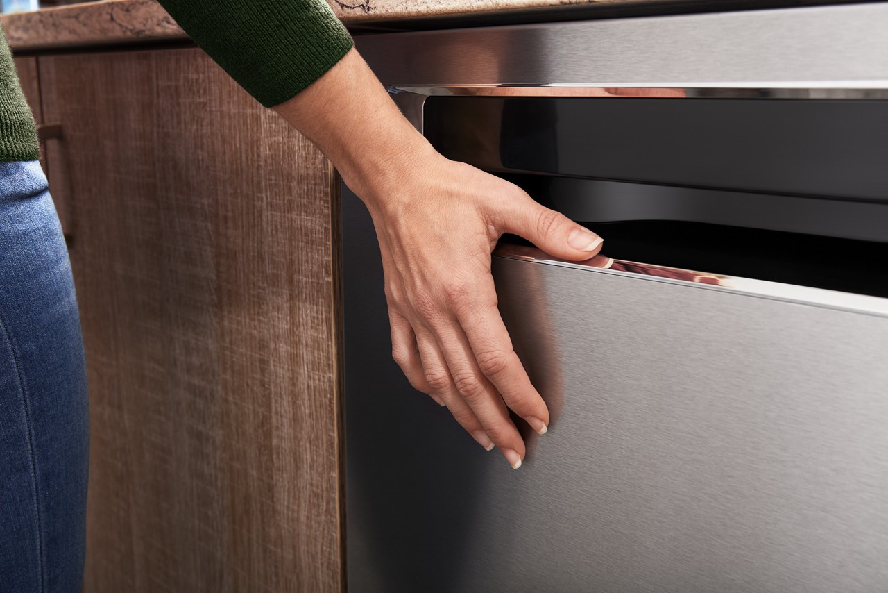 A person closing the KitchenAid KDFM404KPS dishwasher 