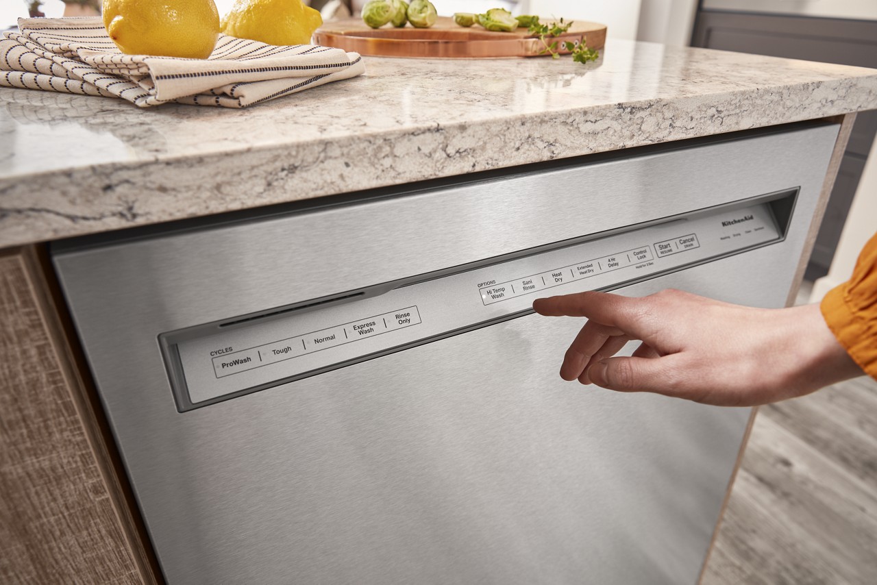 A person selecting a cycle on the KitchenAid KDFM404KPS dishwasher 