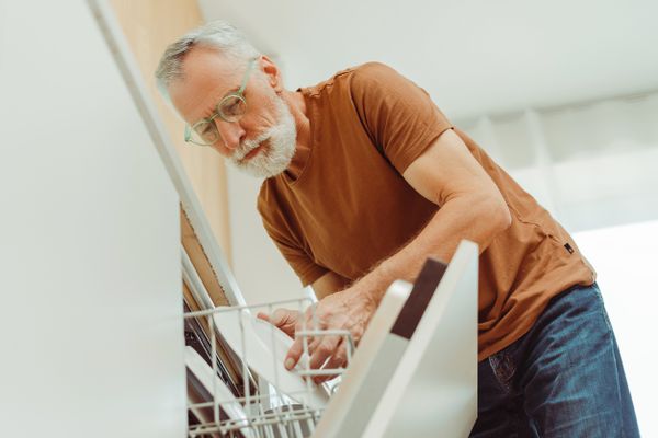 A man grabbing a plate from a dishwasher 