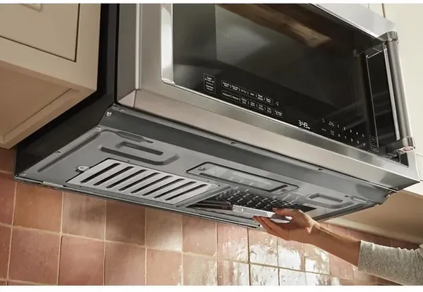 A person removing the filter on the KitchenAid KMHC319LSS over the range microwave 