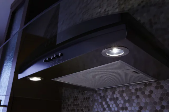 A close up of the Whirlpool WVW51UC0HV black range hood with its lights one 