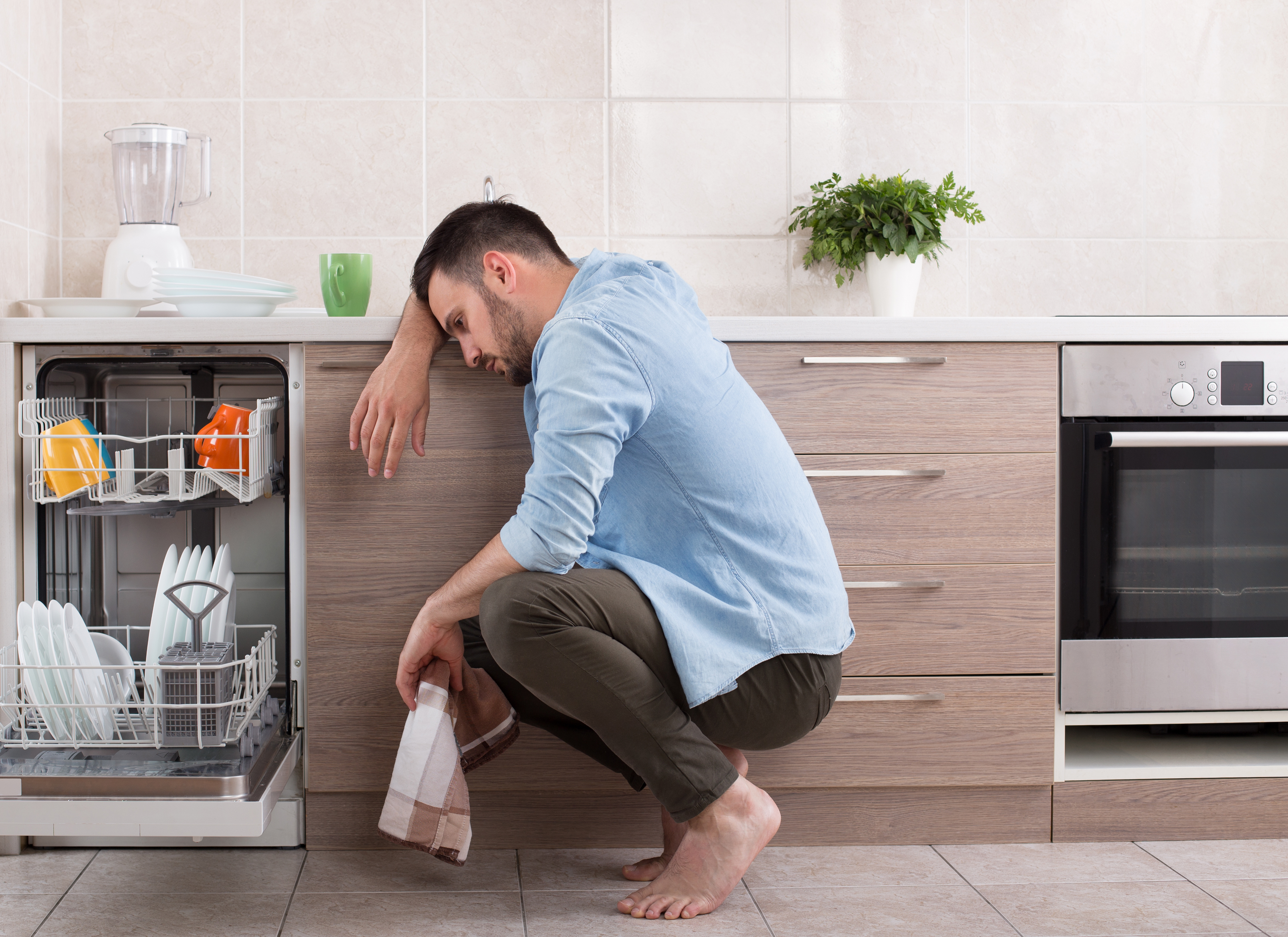 A man works to repair his dishwwasher