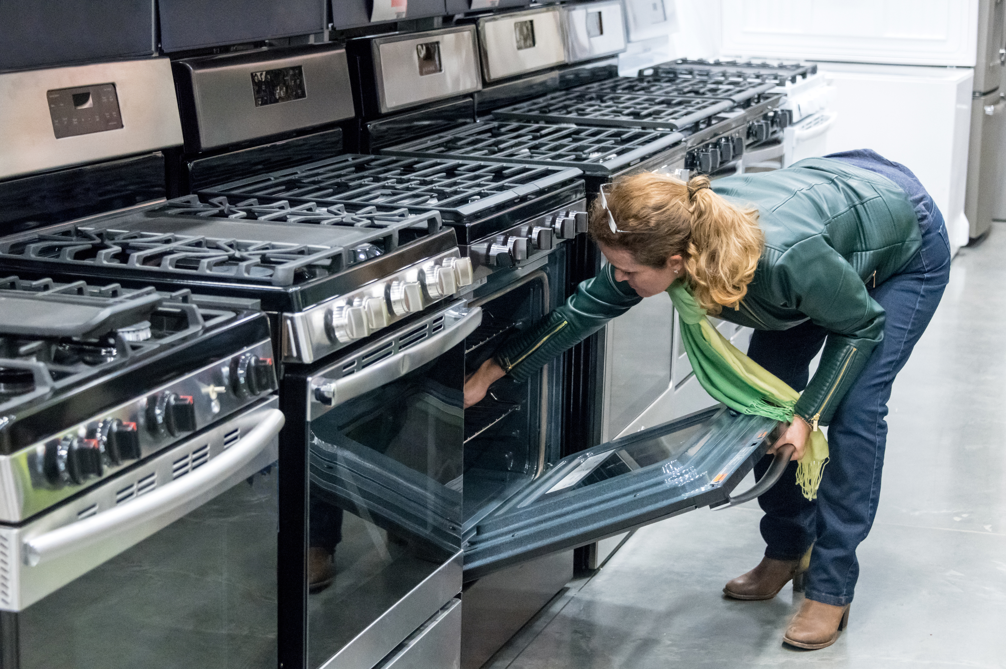 A woman inspecting the interior of a range 