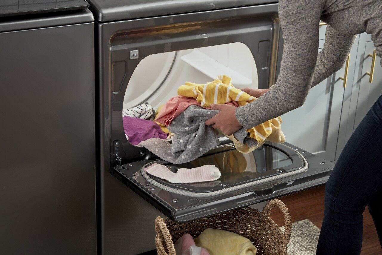 A woman taking clothes out of a Whirlpool dryer 