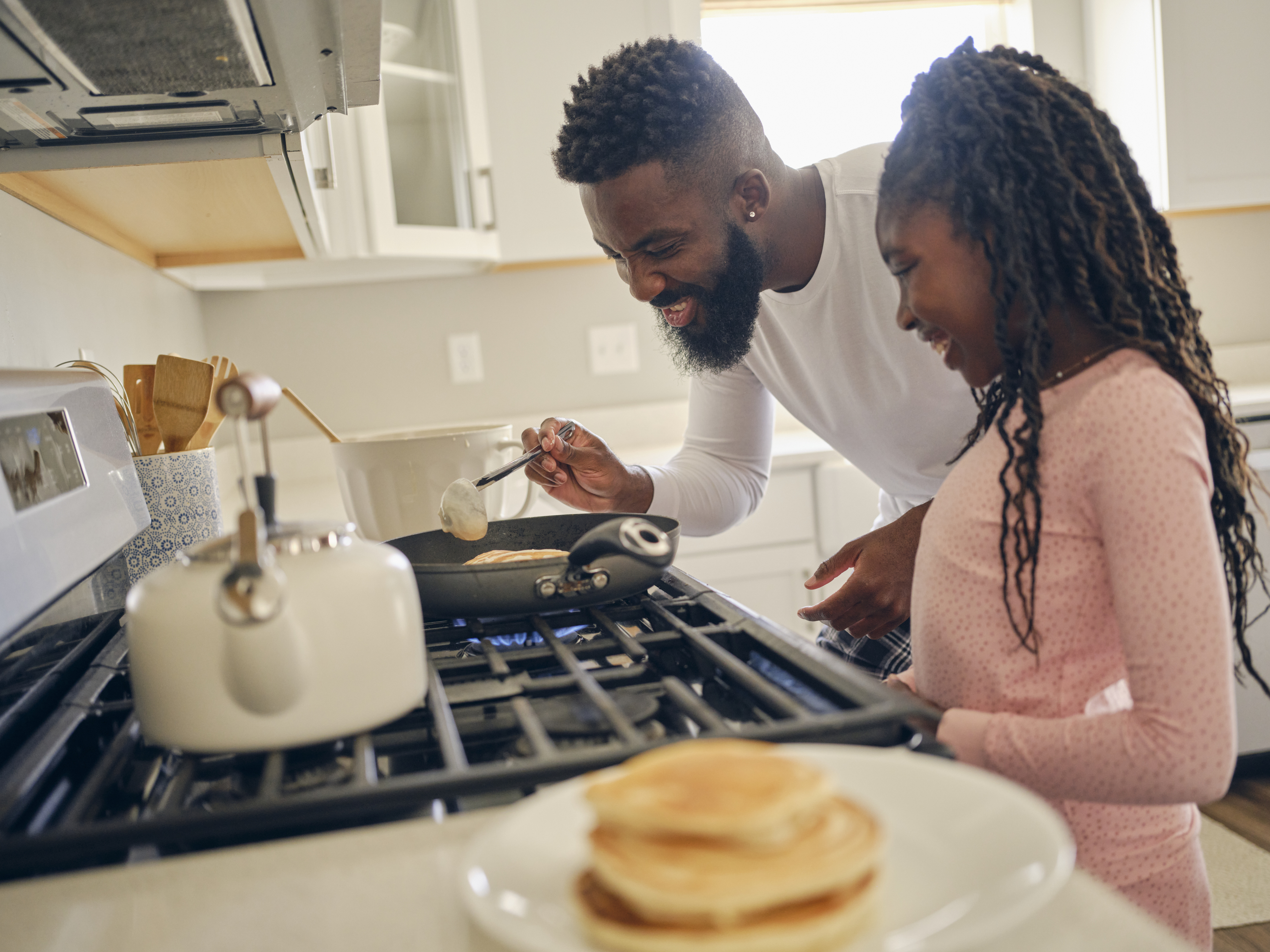 A father and daughter cooking on a gas range 