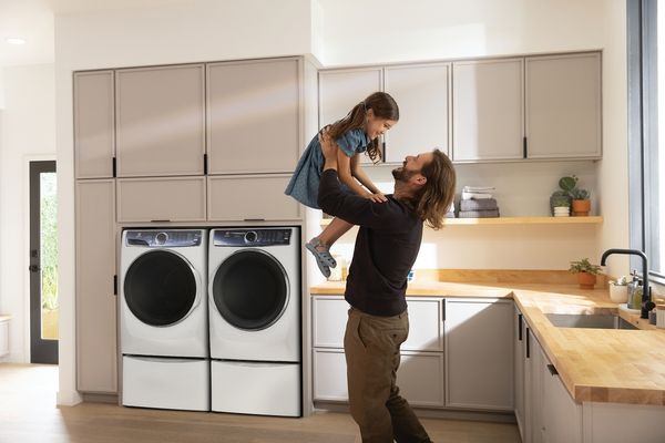 A man tossing a girl in the air in a laundry room with an Electrolux washer and dryer pair 
