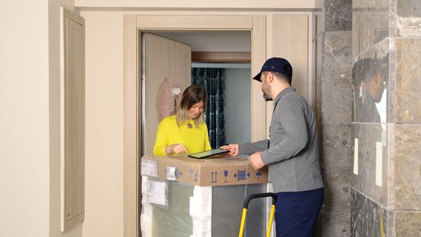 A delivery driver dropping off a washer to a woman 