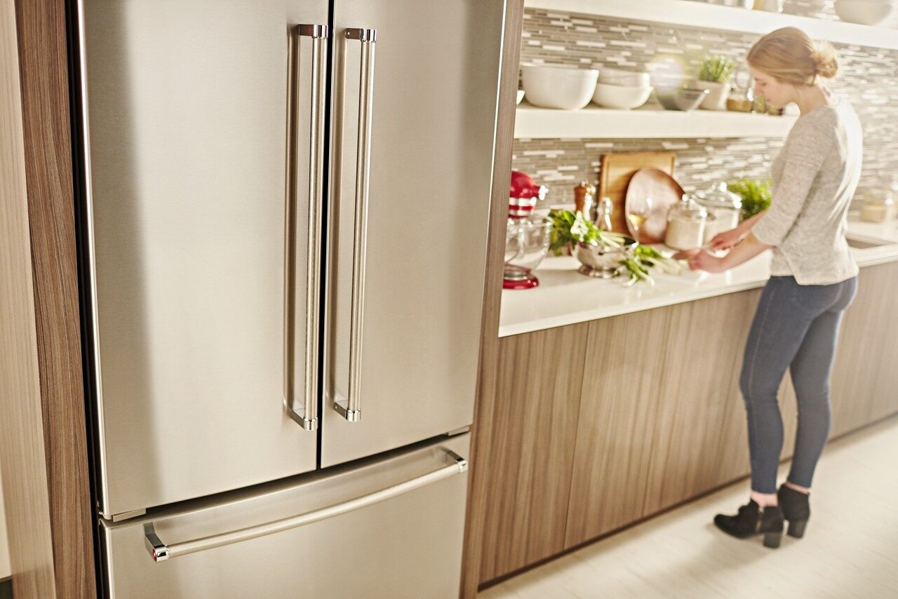 A woman preparing a meal next to the KitchenAid KRFC300ESS French door refrigerator 