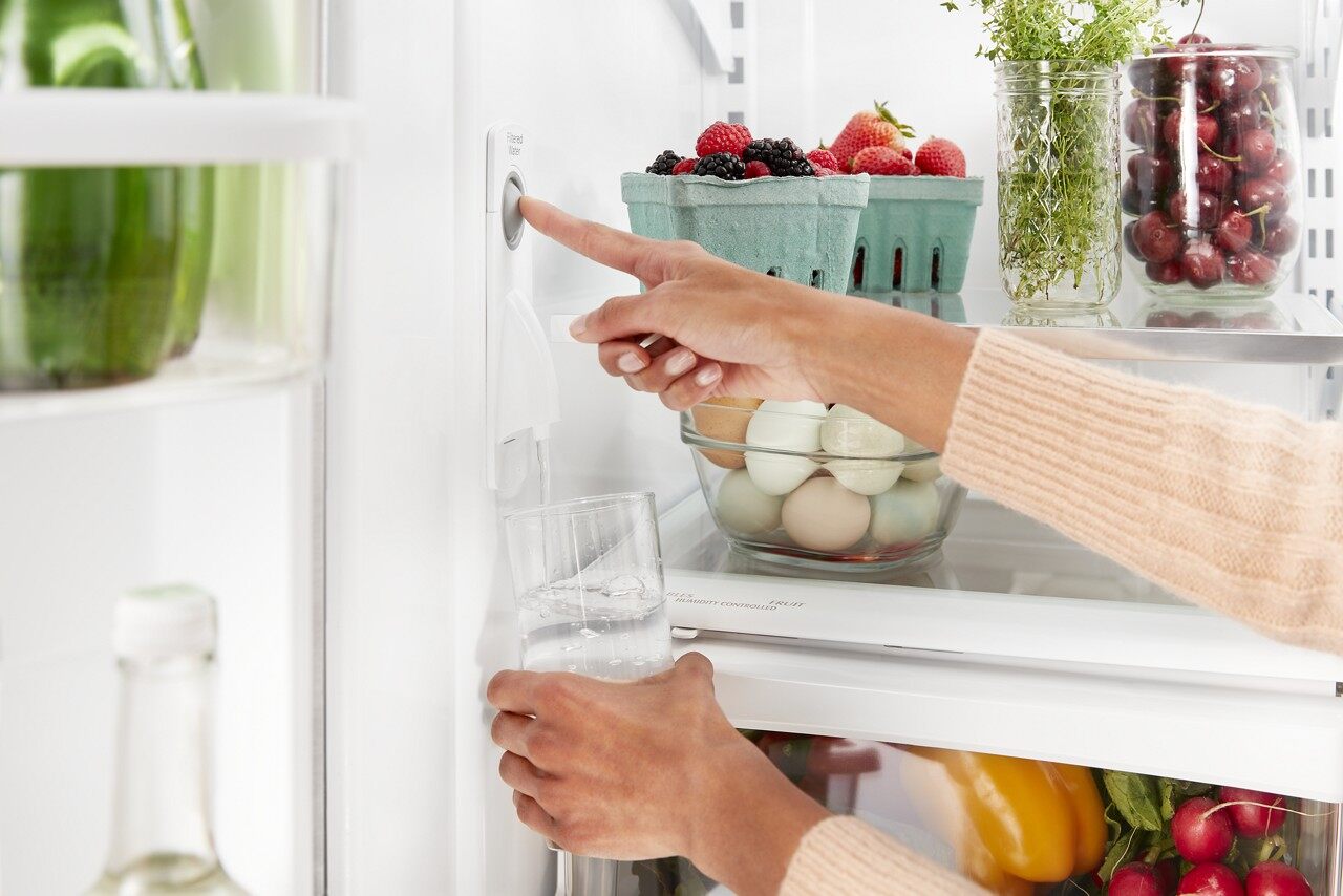 A person using the internal water dispenser on the KitchenAid KRFC300ESS French door refrigerator 